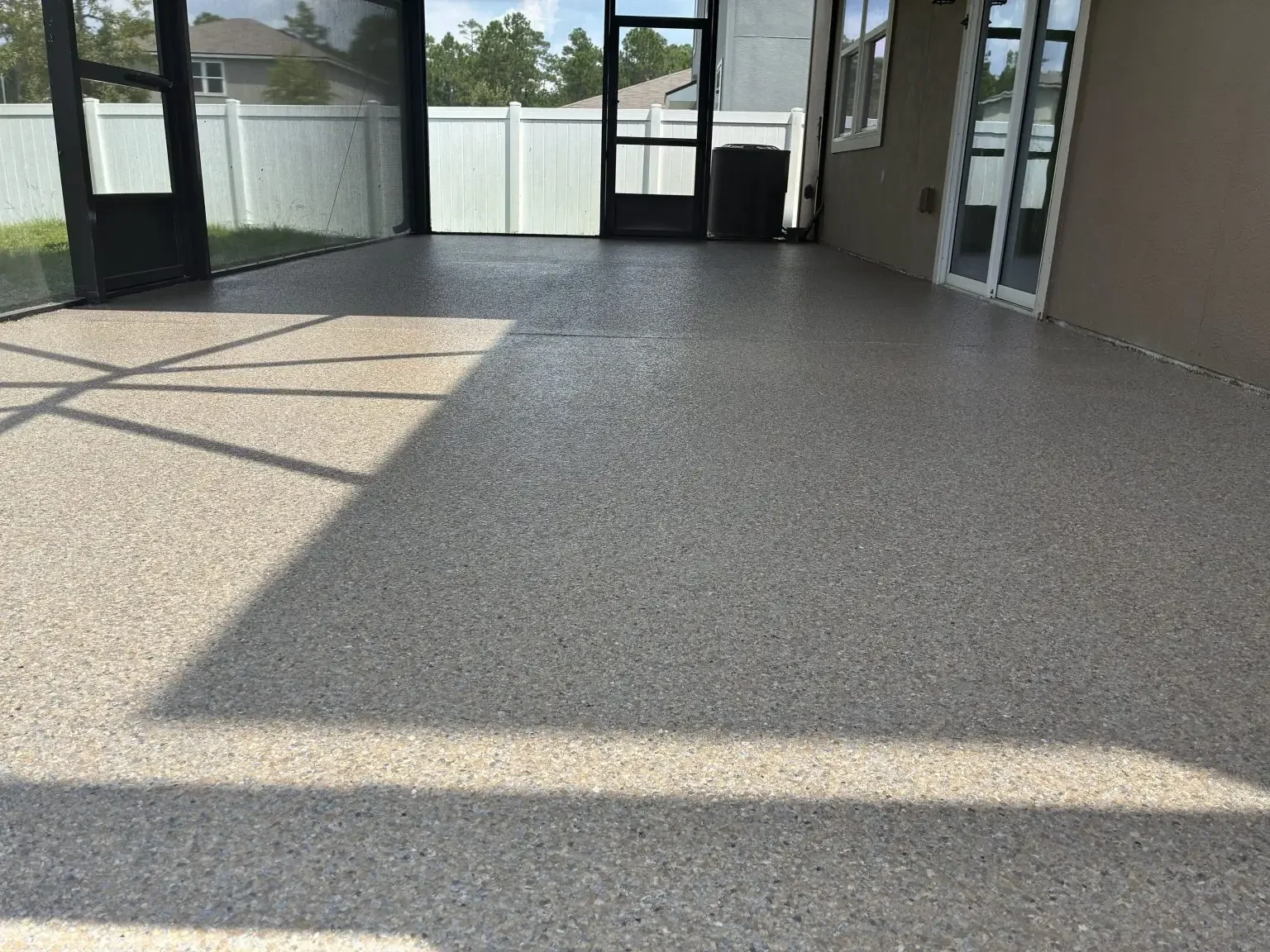 Light gray flake coating on a screen room floor with a white fence beyond