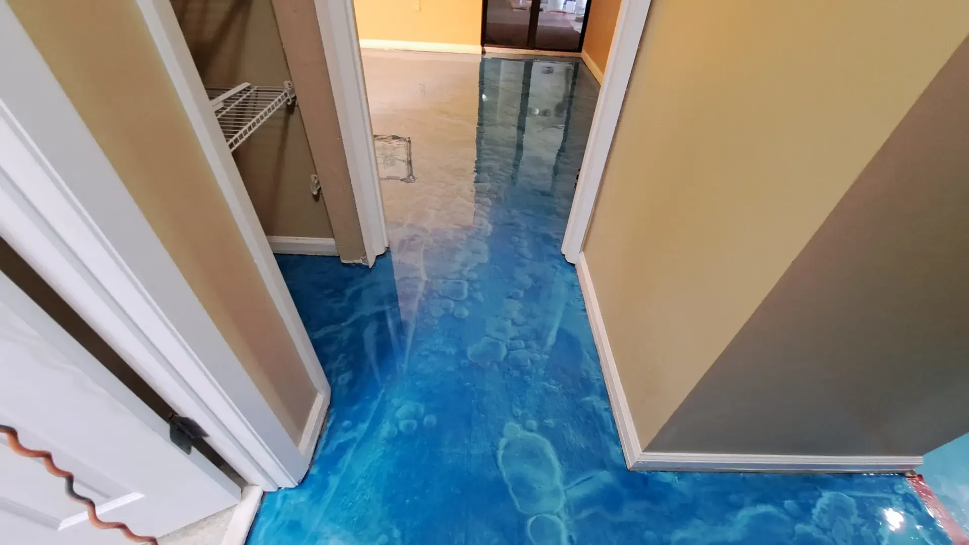 Ocean blue metallic epoxy floor running through a doorway into a hallway