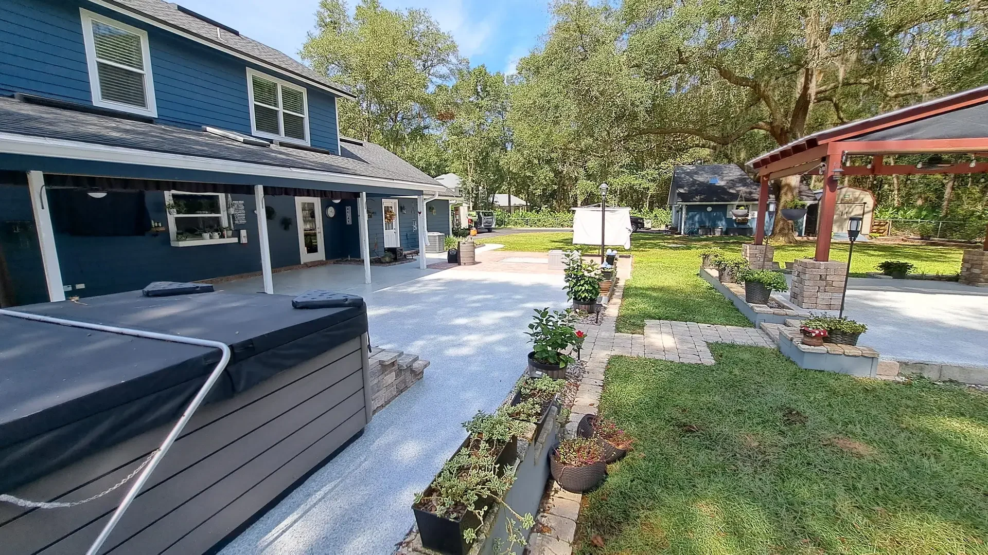 Light gray flake coating on a backyard walkway beside a hot tub and live oaks