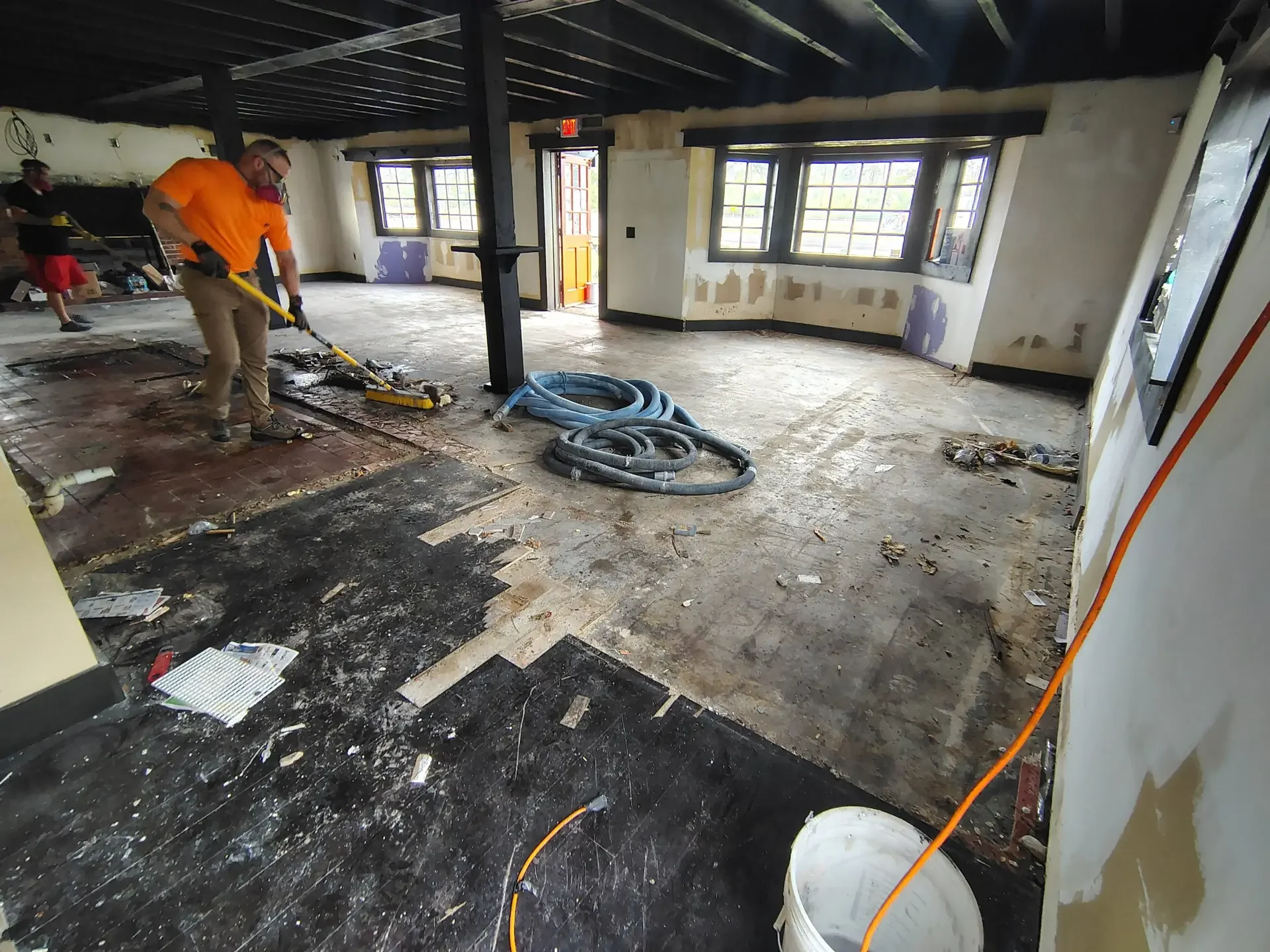 Old flooring stripped off an interior slab before grinding, crew at work